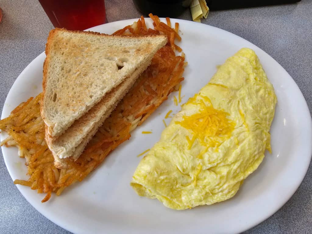 Cheese omelet next to hashbrowns and toast on a white plate