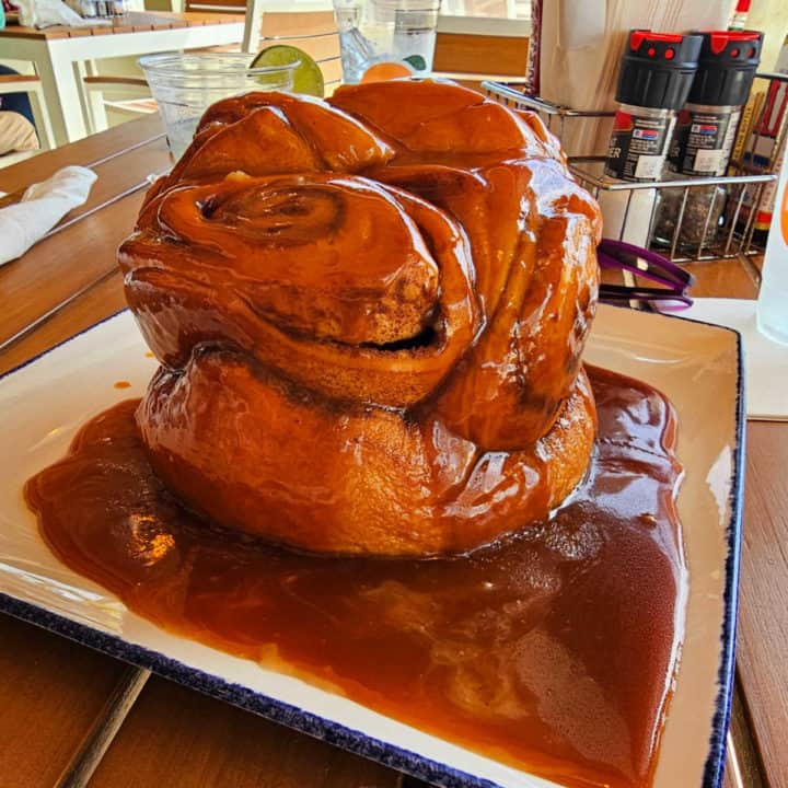 Giant cinnamon bun on a white plate with caramel icing 