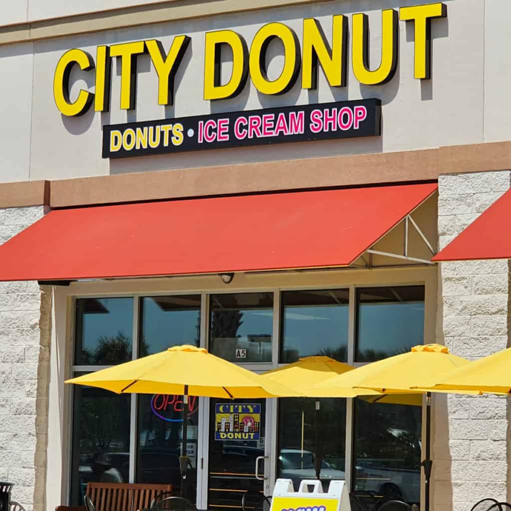 City Donut Donuts Ice Cream Shop with orange awning, and yellow umbrellas over tables