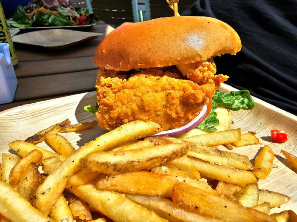 Coastal Chicken Sandwich next to French fries on a wooden table