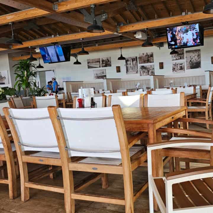 tables and chairs inside CoastAL with art on the wall and two tvs hanging from the ceiling