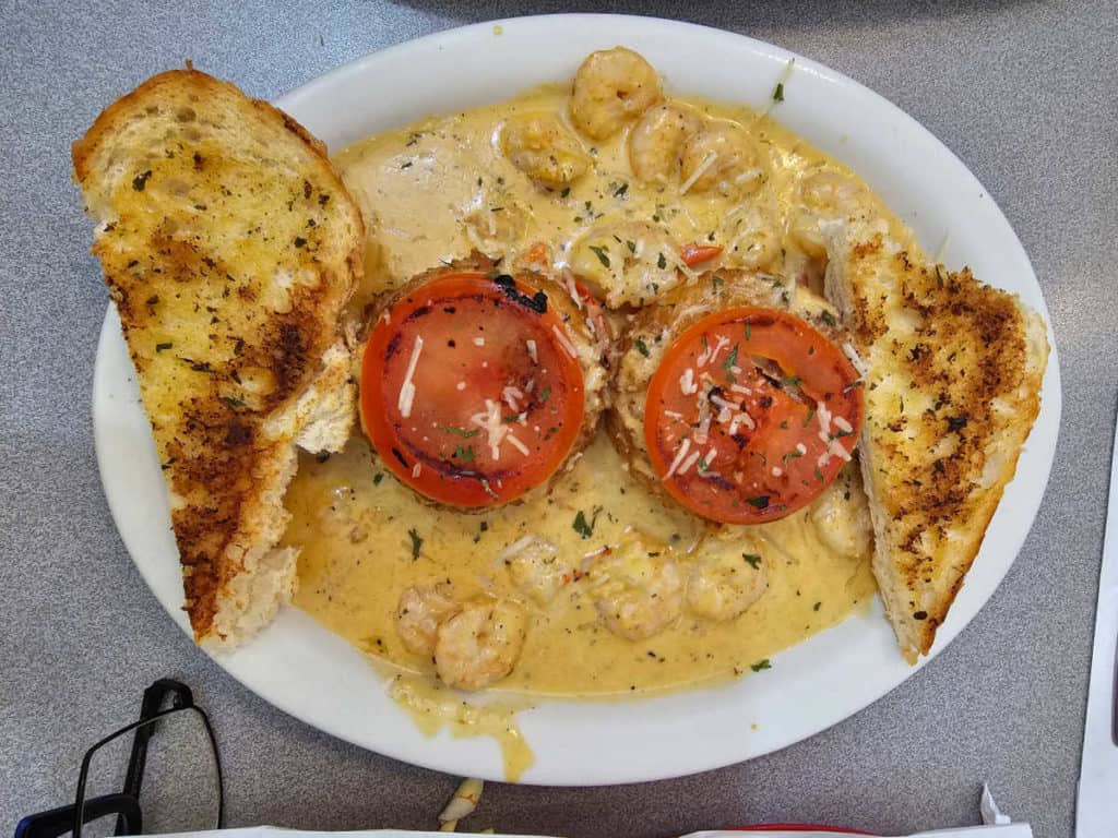 Shrimp and grits topped with grilled tomatoes with a side of garlic toast