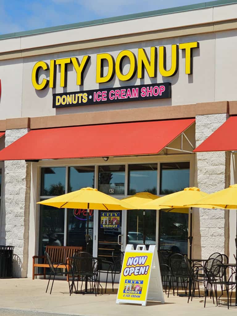 City Donut sign over an orange awning, yellow umbrellas over black outdoor tables and chairs