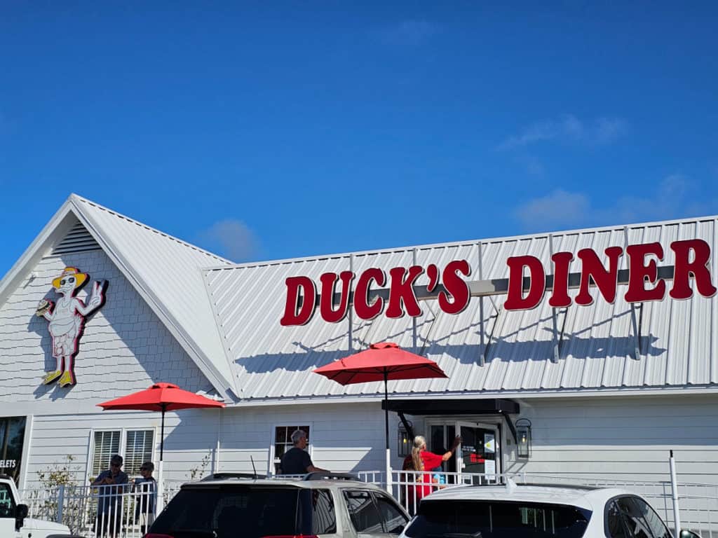 Exterior of Ducks Diner with people waiting outside and red umbrellas