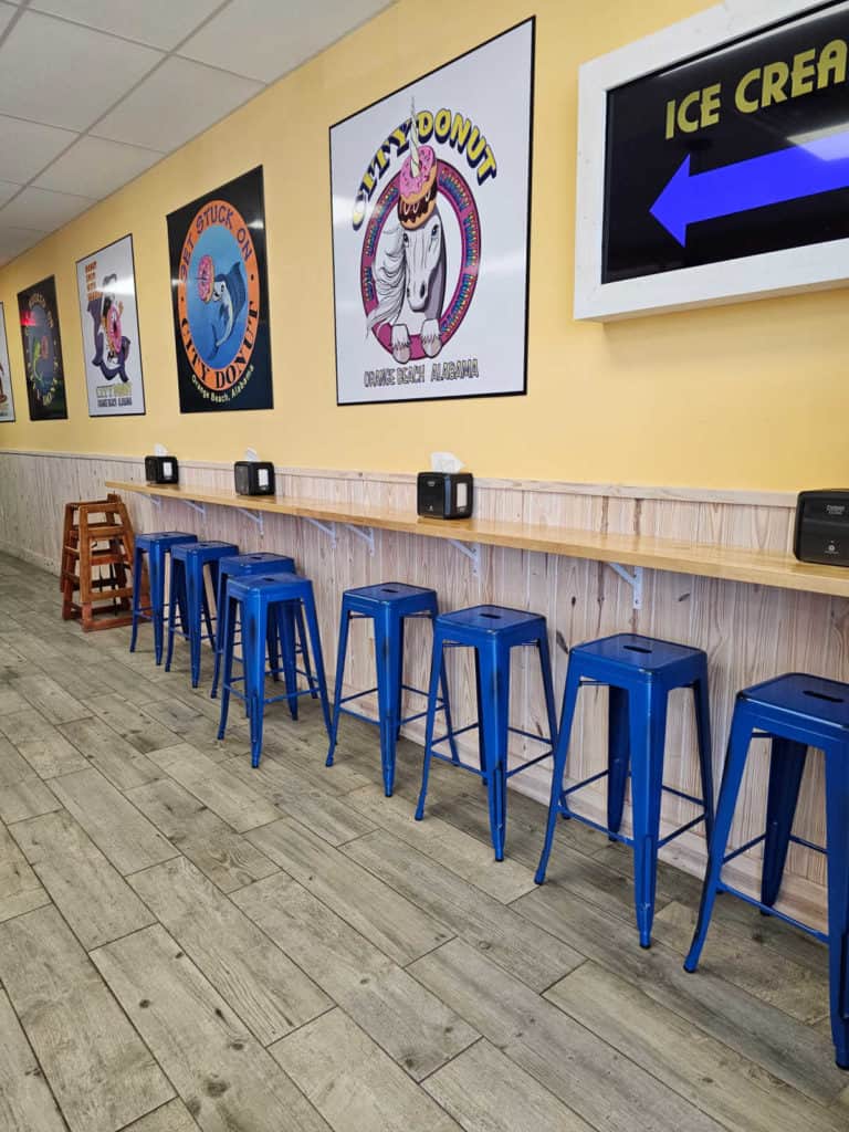 Blue stools under a wood counter with napkins and City Donut signs