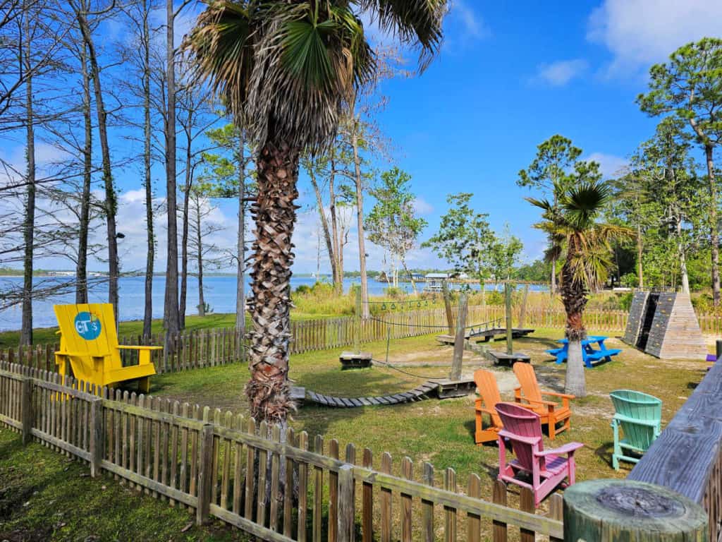 Adirondack chairs with a kids play area, palm trees, and views of Wolf Bay