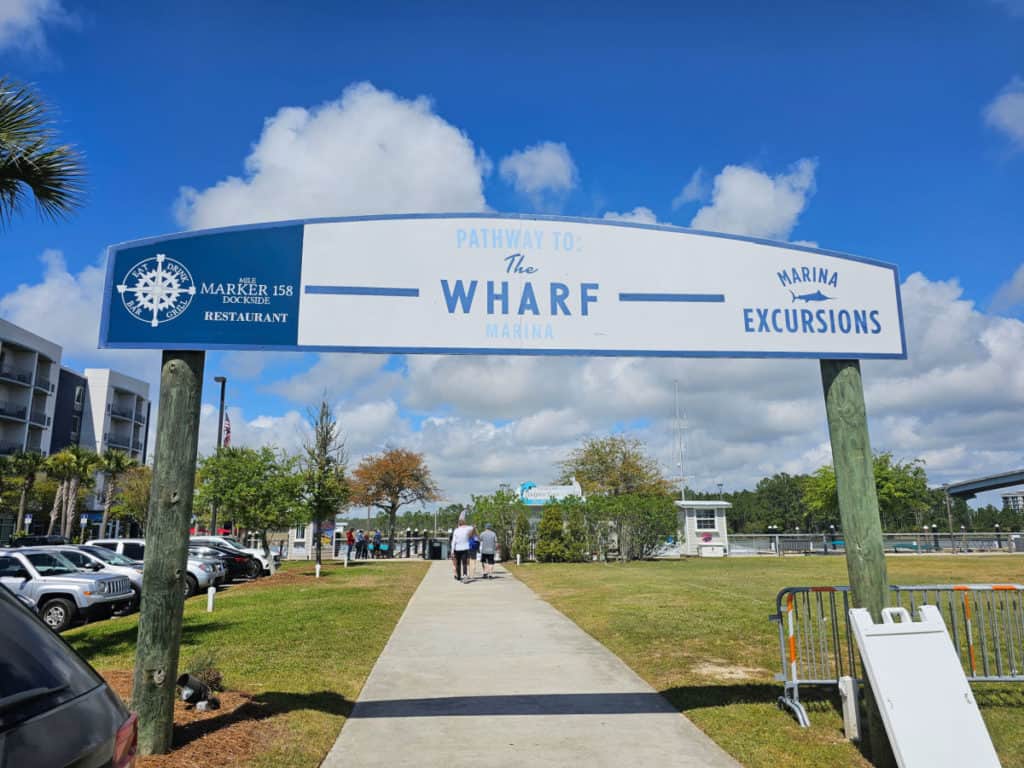 Pathway to the Wharf sign over a paved walkway with two people walking