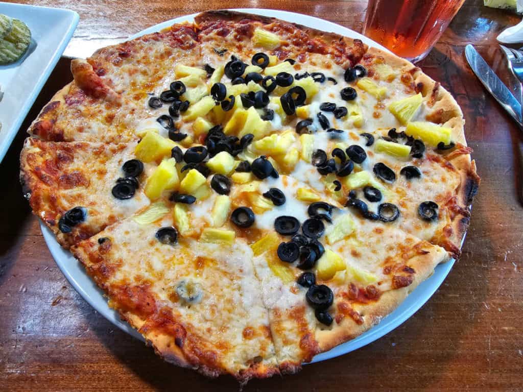 Wood fired pizza with black olives and pineapple