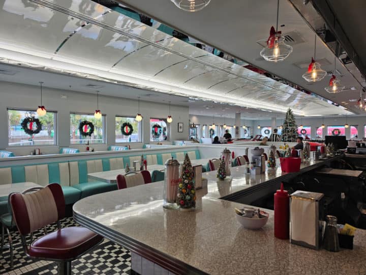 Looking over a diner bar to booth seating and wreaths hanging in the windows