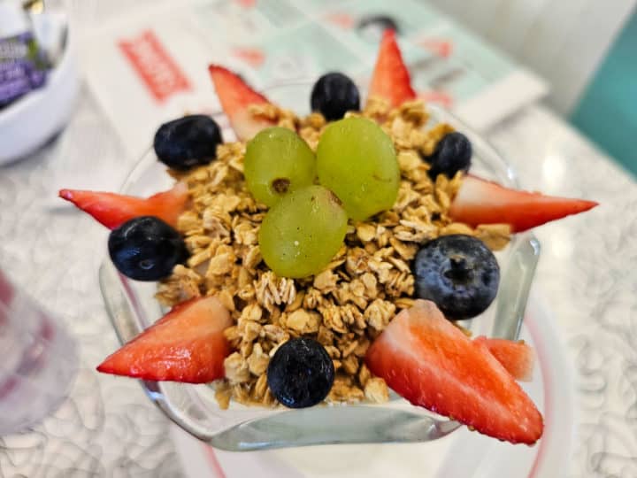 yogurt parfait with grapes, granola, blueberries and strawberries on top. 