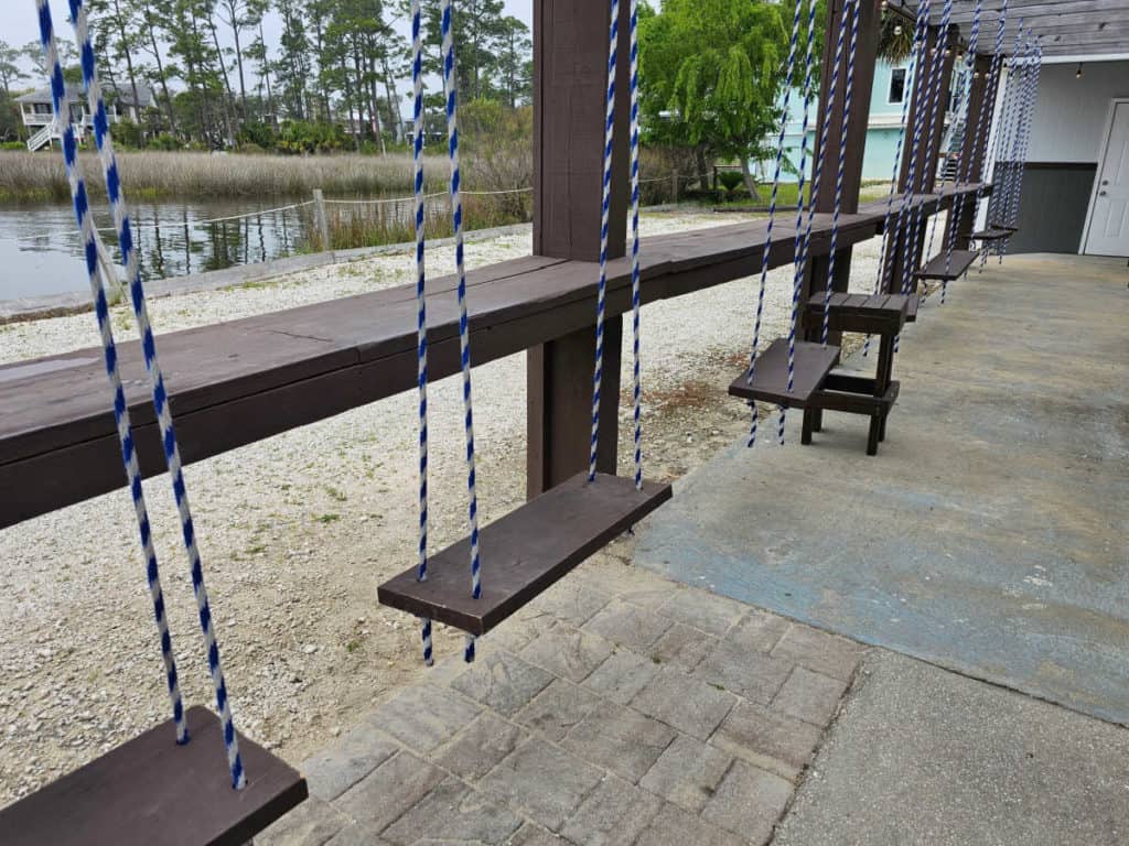 Swing seats along an outdoor bar with water in the background
