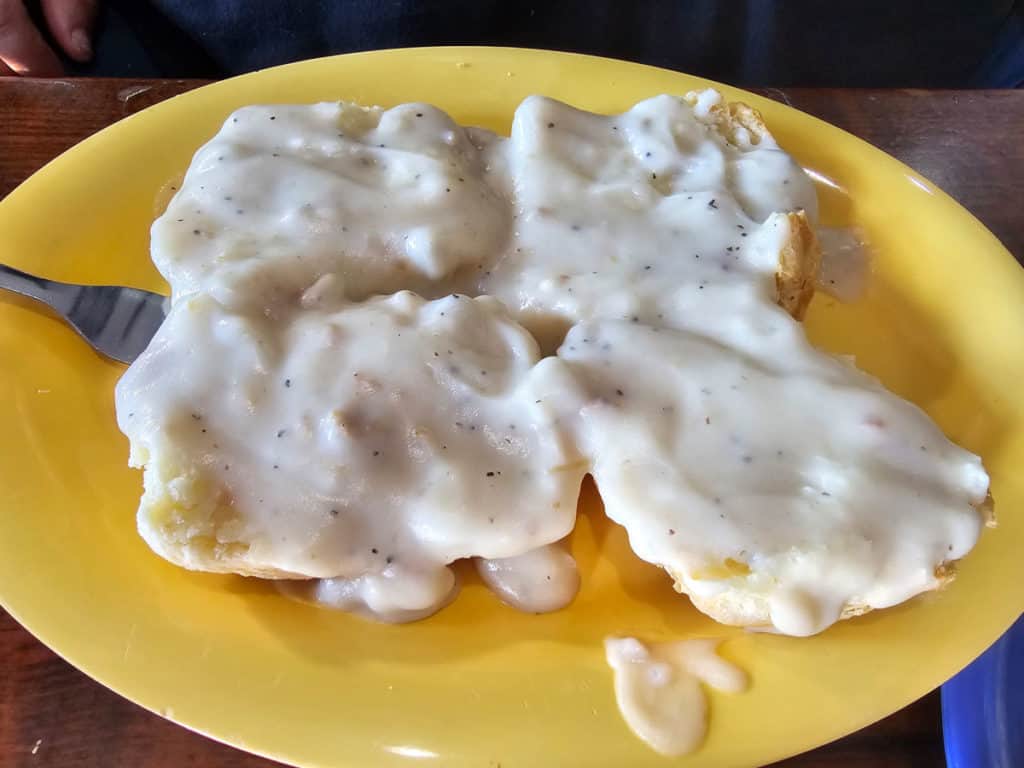 Biscuits and gravy on a yellow plate with a fork