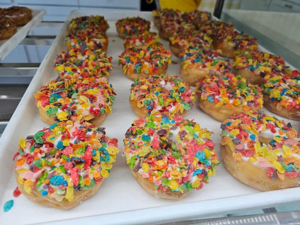 Fruity pebbles doughnuts on a white tray at Daisy's Donuts