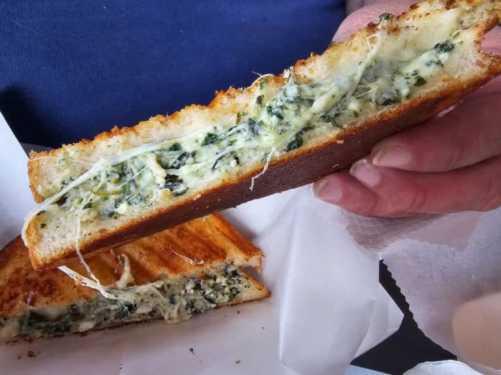 Grilled cheese with spinach held up above a 2nd half of the sandwich