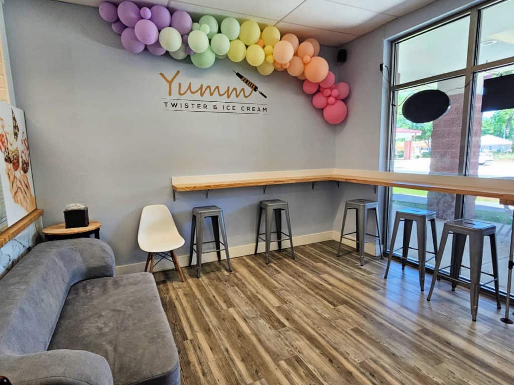 grey couch and bar stools near a wood counter with rainbow balloons on the wall