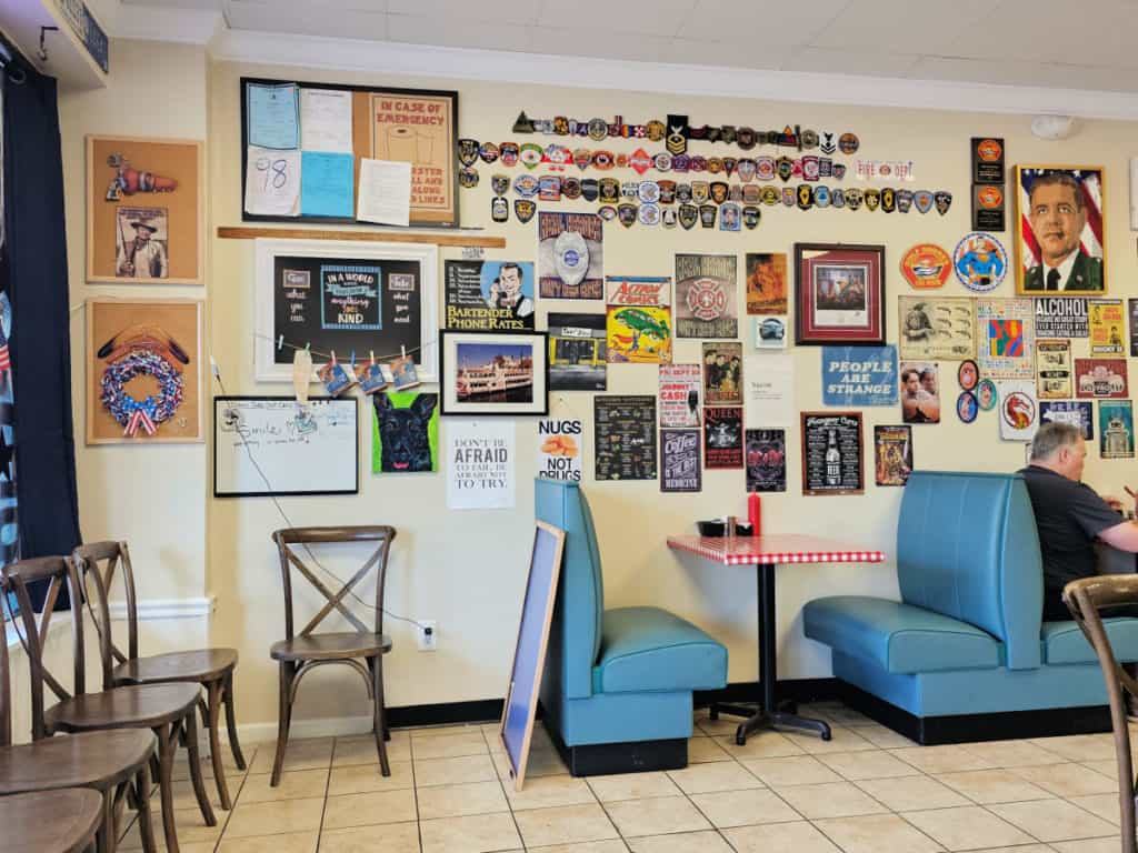 interior seating with booths and chairs in The Ugly Diner with the walls covered in signs and patches