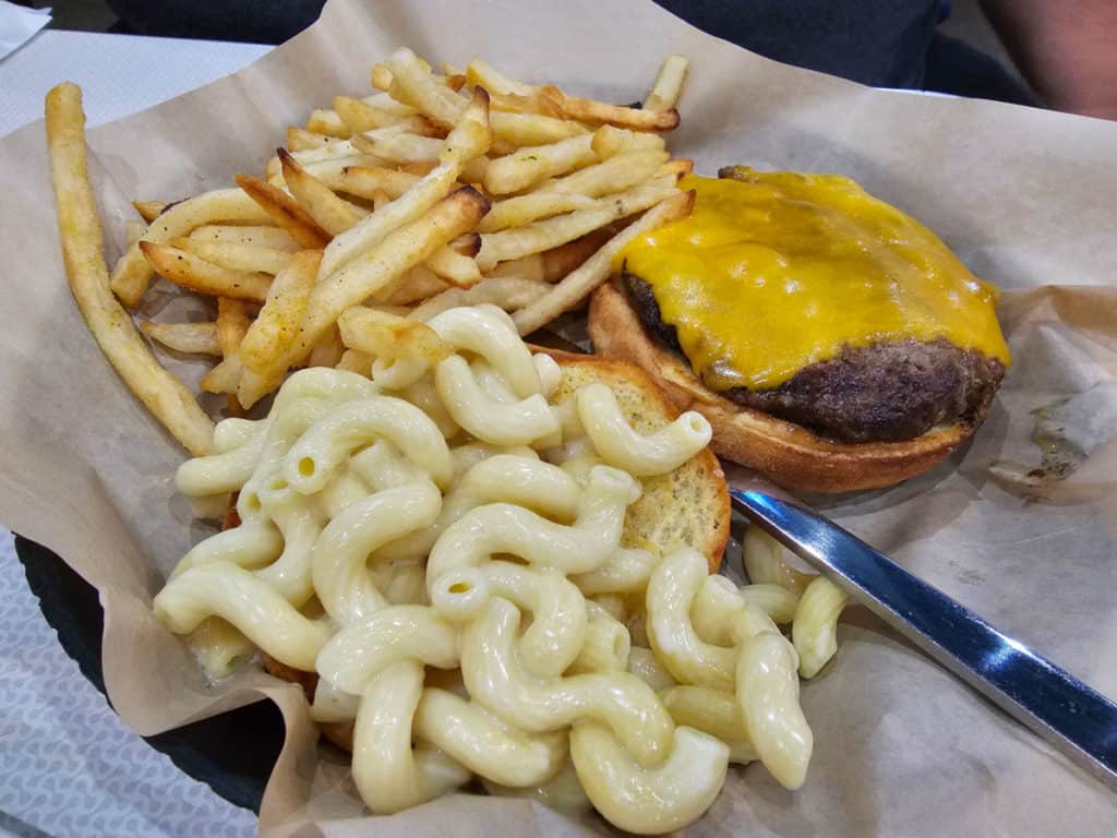 French fries next to a burger next to a mac and cheese topped bun at Island Wing Company