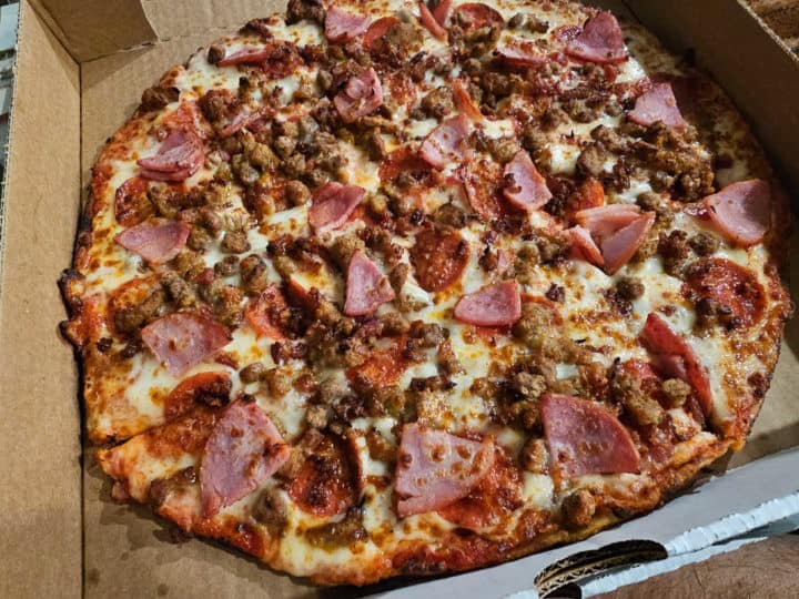 Meat pizza in a cardboard delivery box