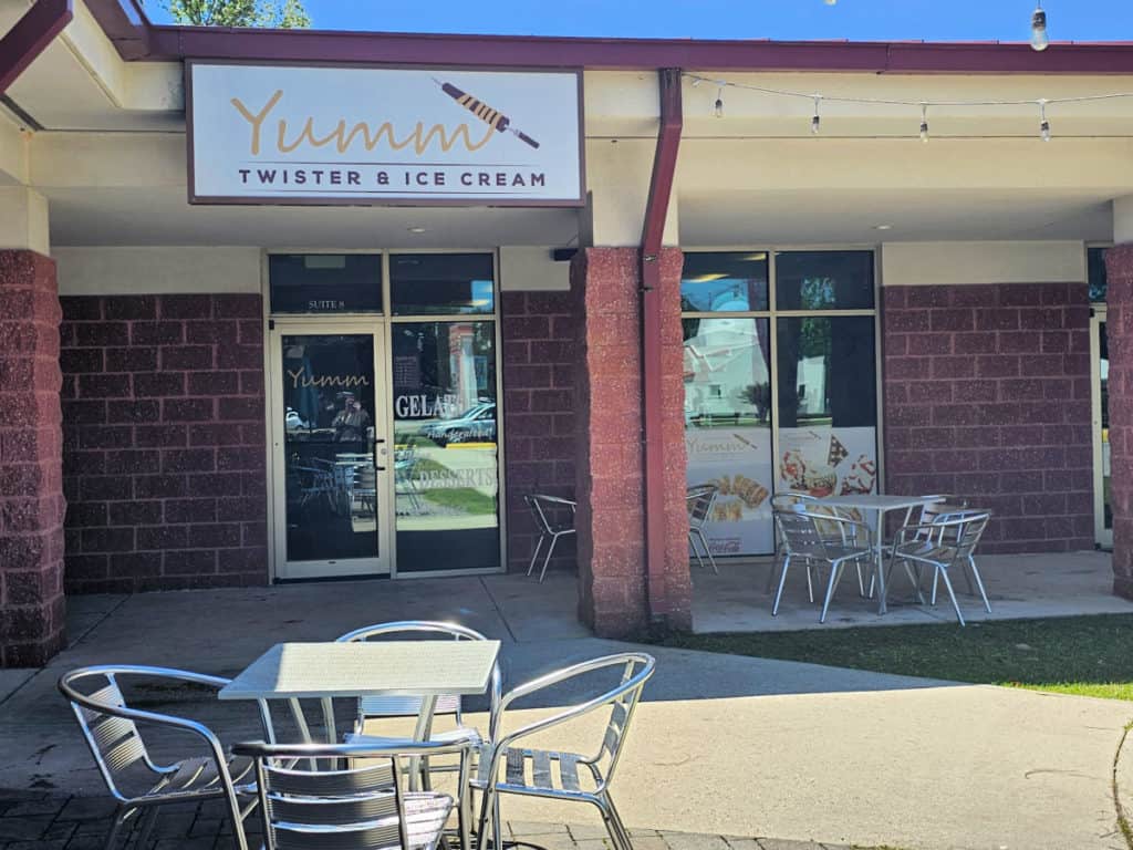 outdoor seating with metal table and chairs next to the Yumm Twister and Ice Cream sign