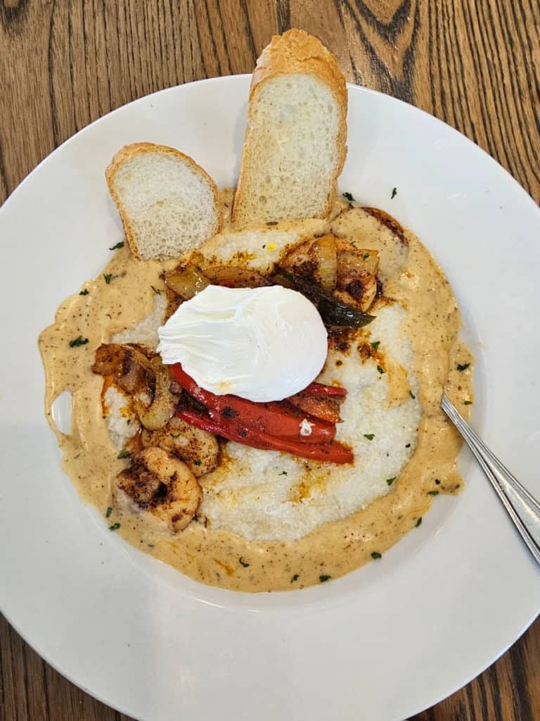 Shrimp and Grits with a poached egg and toast in a white bowl