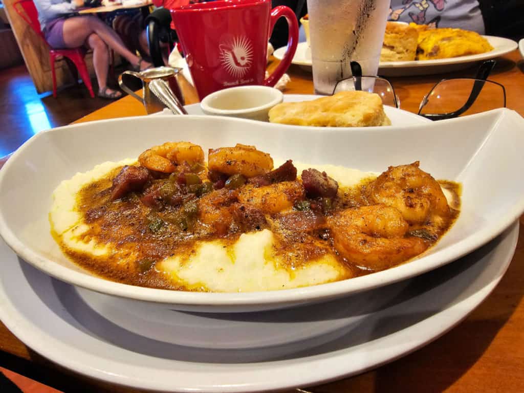 Shrimp and Grits in a white bowl next to a red coffee mug