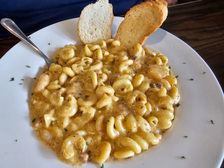 mac and cheese in a white bowl with two pieces of bread