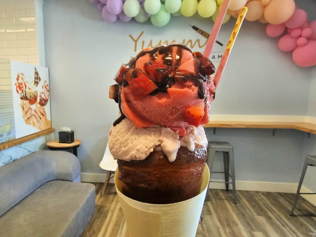 Strawberry Gelato cone in a twister cone with balloons in the background