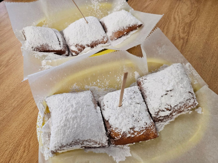 beignets on parchment paper in a basket on a table