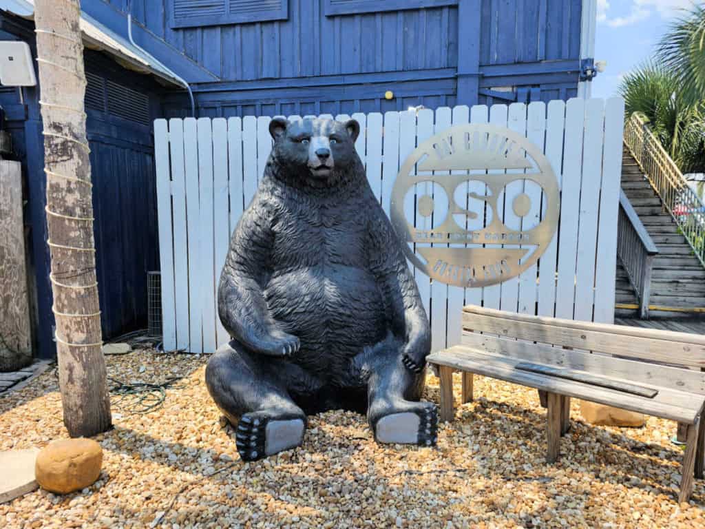 bear statue outside of Oso restaurant next to a picnic bench. 