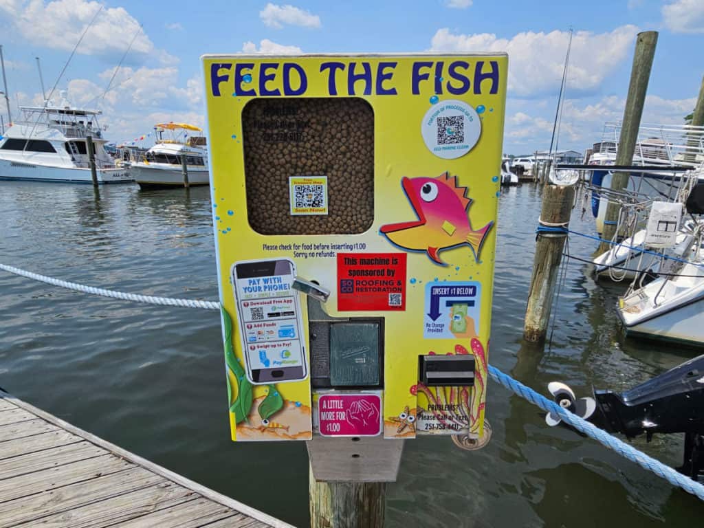 Feed the fish yellow machine with a fish and stickers on it next to the water