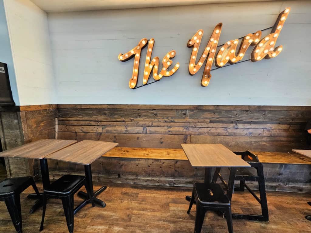 The Yard sign above a wooden bench, tables and chairs at The Yard milkshake bar