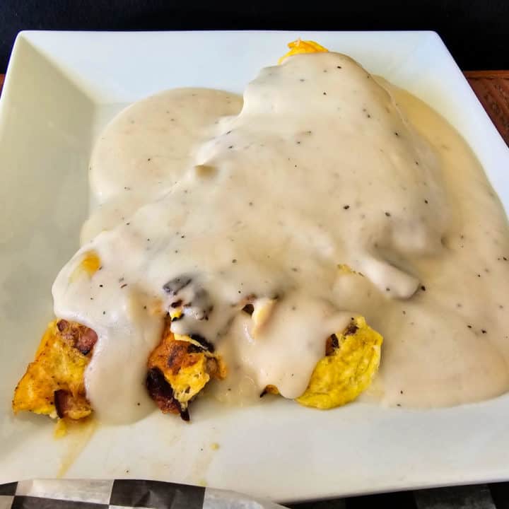 Omelet covered in gravy on a white plate