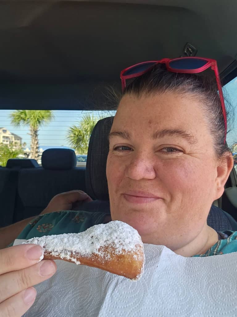Tammilee holding a beignet with a napkin