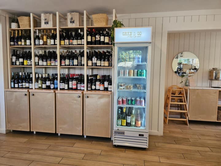 wine bottles on shelves next to a glass cooler