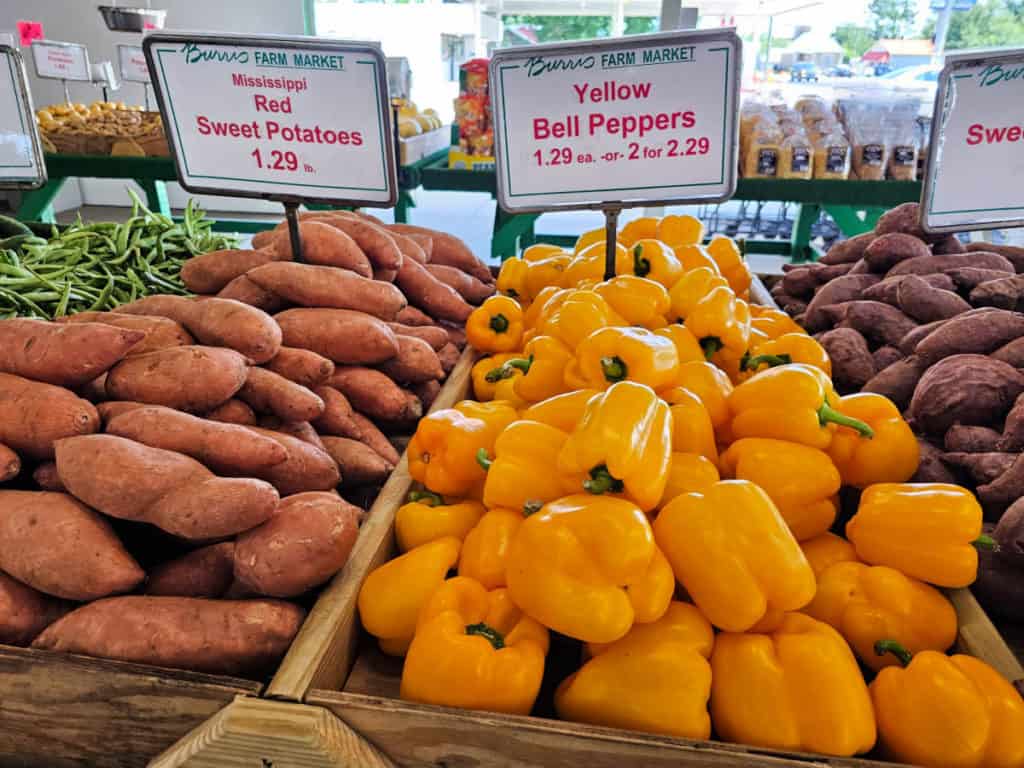 Yellow bell peppers and sweet potatoes in a tray at Burris Farm Market