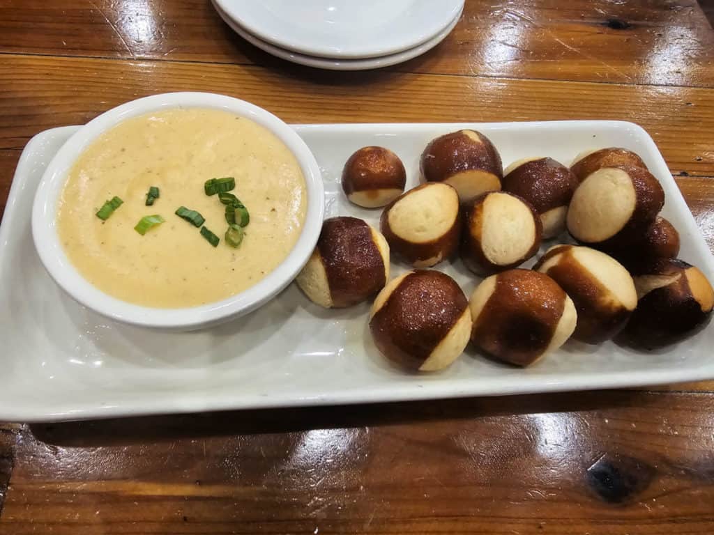 Beer cheese dip with pretzels on a white platter