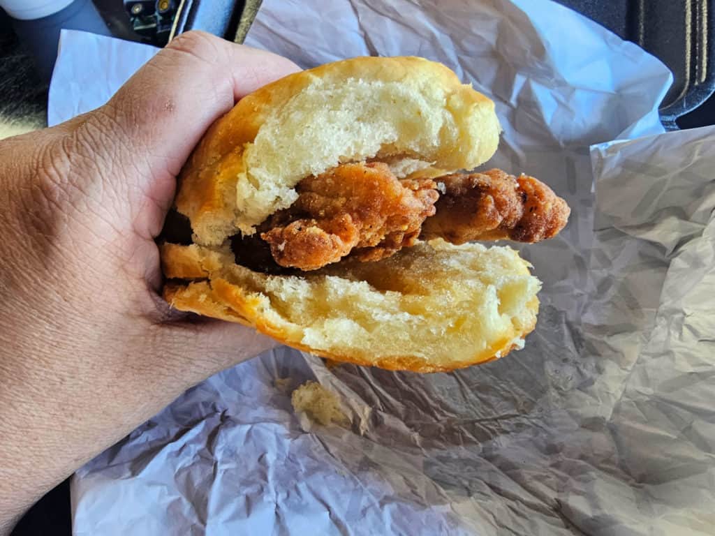 Hand holding a chicken biscuit with honey
