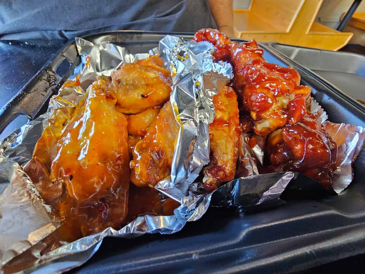 Chicken wings wrapped in foil in a to go container