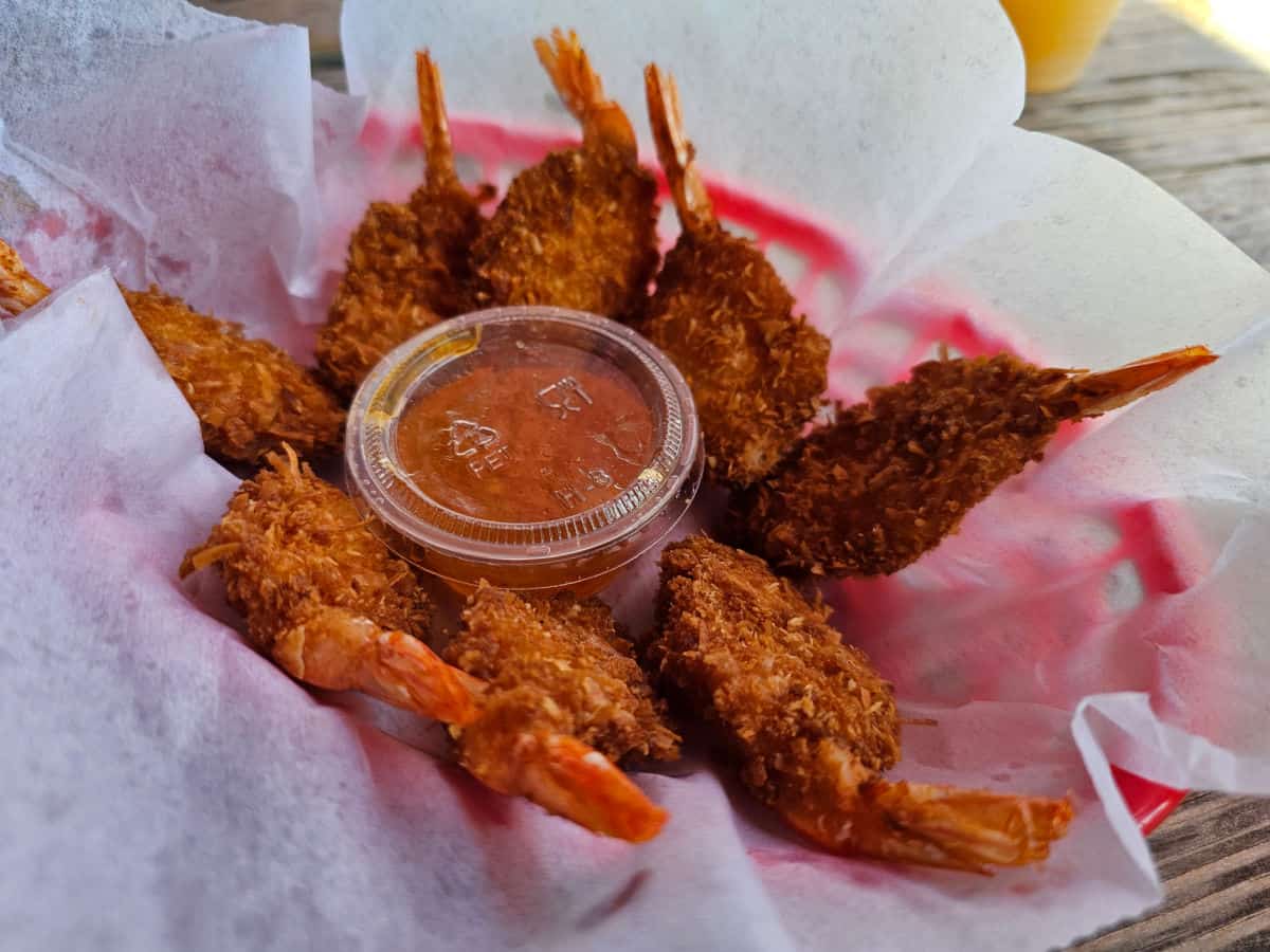 Coconut shrimp with cocktail sauce in a paper lined red basket