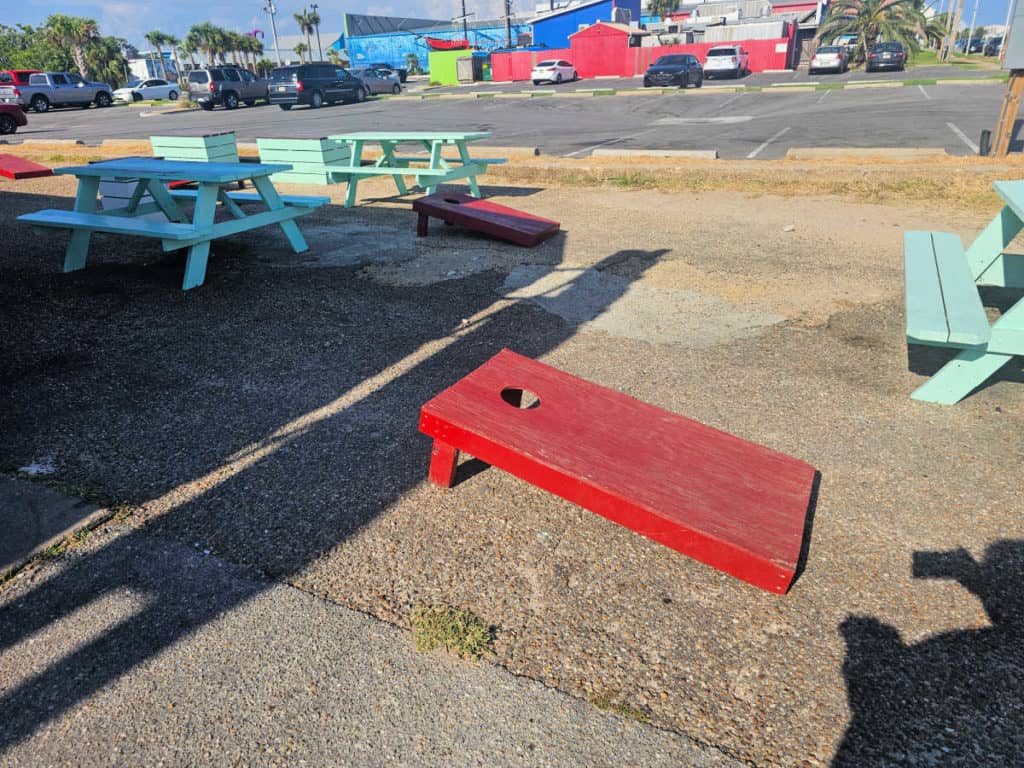 red cornhole games and turquoise picnic tables outside of cherry on top