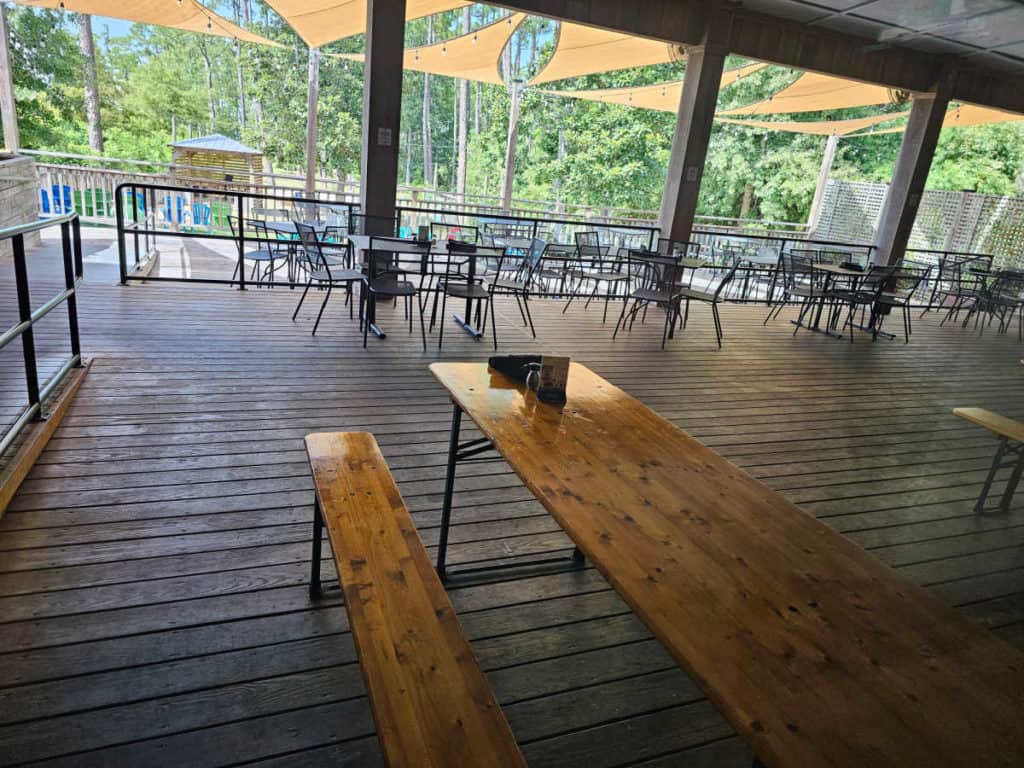 outdoor seating with picnic tables and tables and chairs on a wooden deck at Luna's Eat & Drink