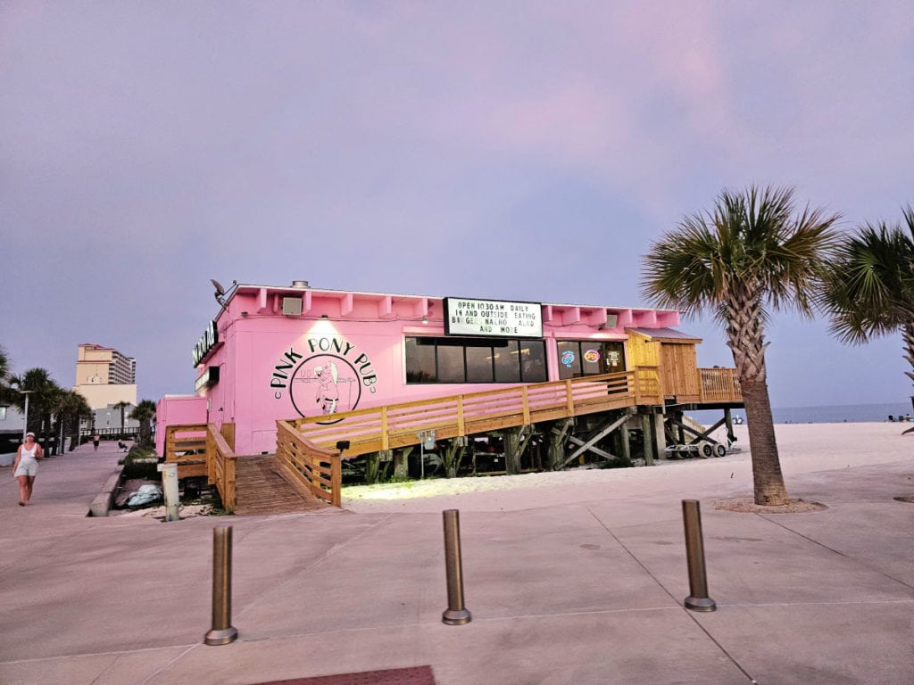 Bright pink exterior of Pink Pony Pub at sunset with palm trees