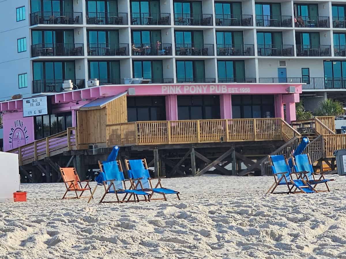 Looking across the sand and beach chairs to the Pink Pony Pub and a hotel behind it