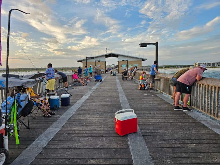 people fishing and looking over the pier with a cooler in the walkway