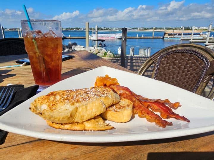 French Toast and Bacon on a white plate with a cup of tea and views of the water