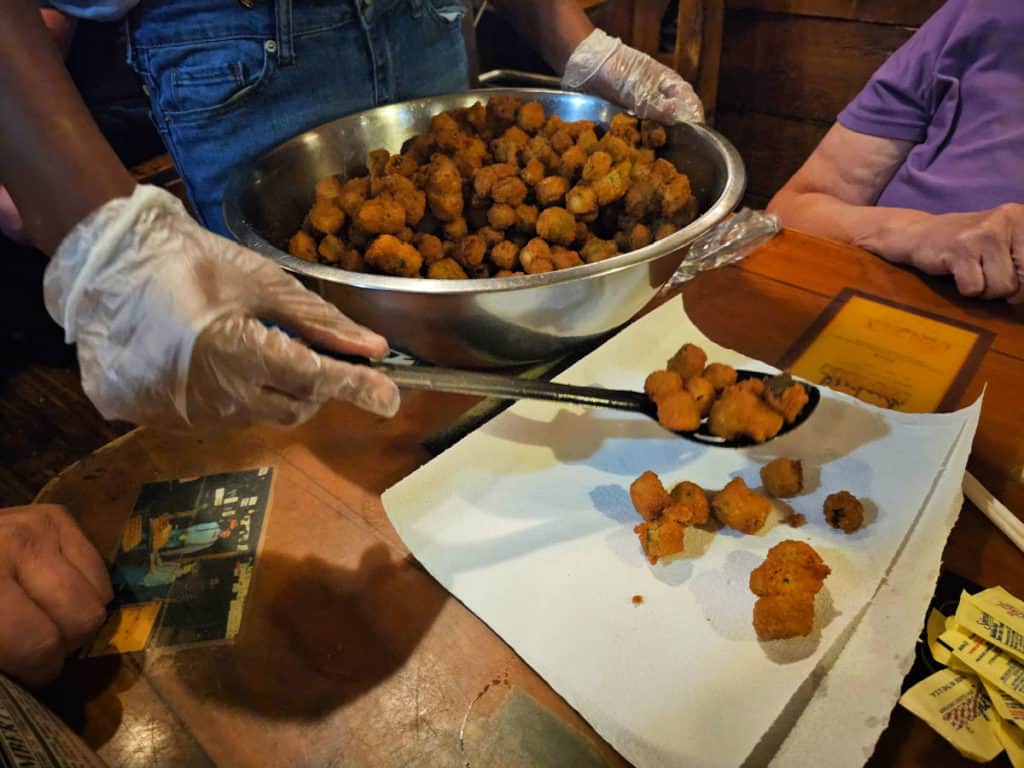 Fried Okra in a silver bowl being served to a paper towel on a table