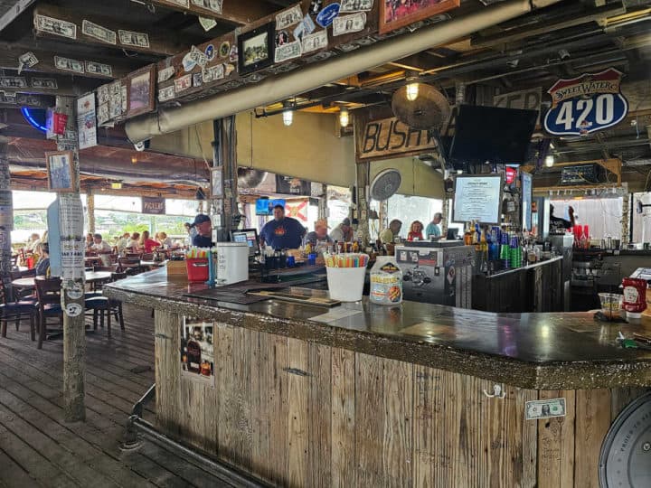 indoor wooden bar inside the Flora Bama Yacht Club next to tables and chairs