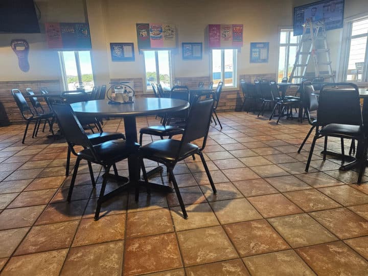 indoor seating with tables and chairs, light coming through the windows by Lillian's Pizza t-shirts on the wall