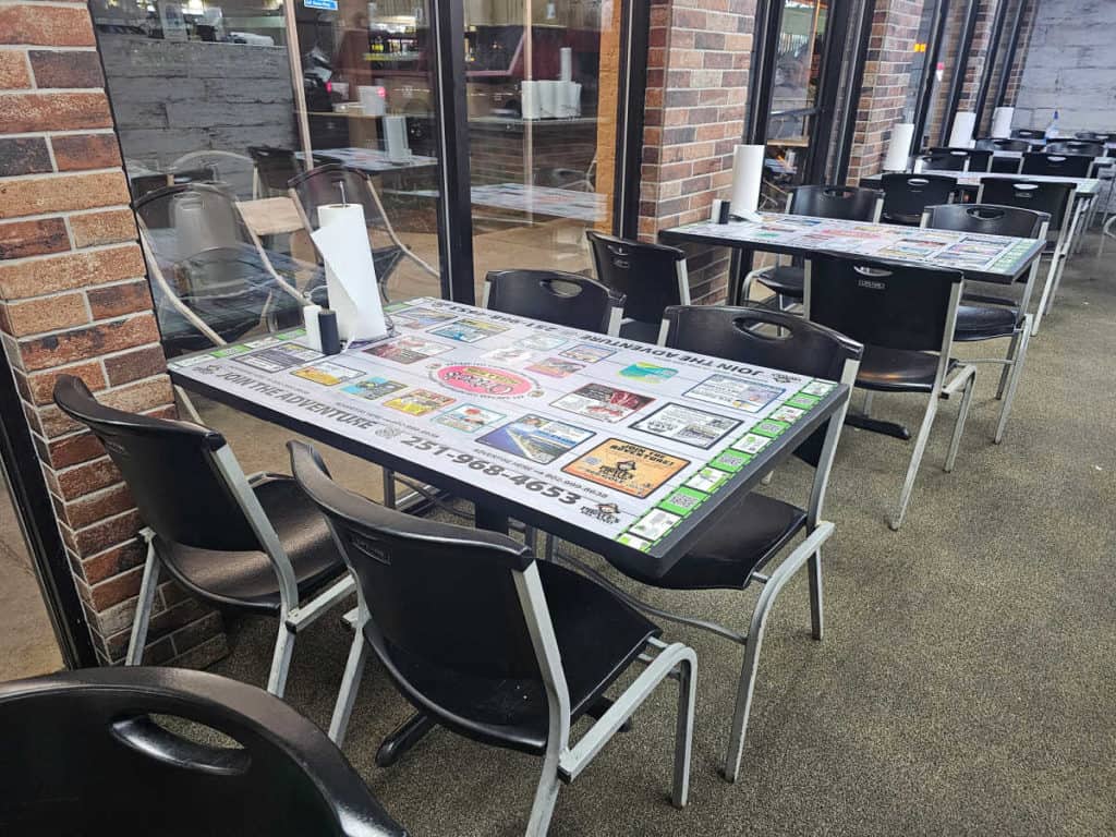 Tables covered with advertisements and chairs in Cricos Pizza