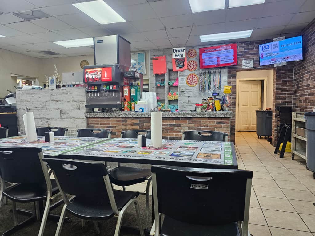 Inside of Cricos Pizza with tables and chairs, order counter
